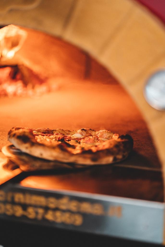 Firery wood oven with fresh pizza